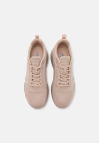 Beige sportcipők texturált hálós felsőrésszel, fűzős designnal és húzófüllel a sarokrészen; a nyelvén található a logó.