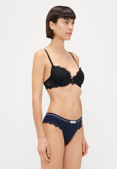 Reggiseno in pizzo nero con ferretto, caratterizzato da un bordo scallop e spalline regolabili, abbinato a slip blu navy con bordo in pizzo.