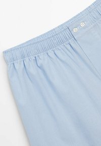 Boxers à carreaux bleu clair avec une taille élastique et deux boutons à l'avant. Tissu doux avec une texture lisse.