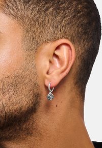 Silberne Creole mit einem Rosendesign. Sie weist feine Details an der Rose und eine polierte Oberfläche auf und hängt an einem runden Hoop.