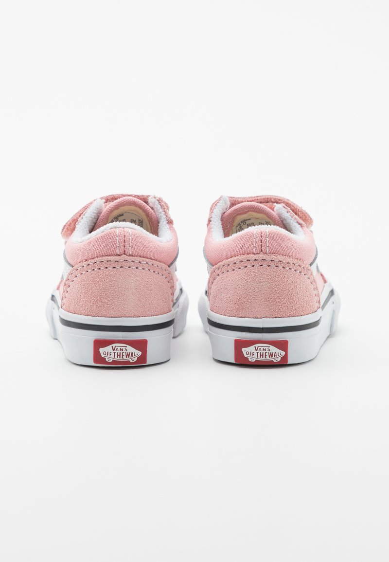 Lichtroze suède sneakers met witte textiele accenten, voorzien van een zachte kraag, klittenbandsluitingen en een rood Vans-logo op de hiel.