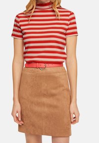 Camisa de manga corta a rayas rojas y beige con cuello en forma de ola, combinada con una mini falda de ante color marrón y un cinturón rosa a juego con una hebilla redonda.