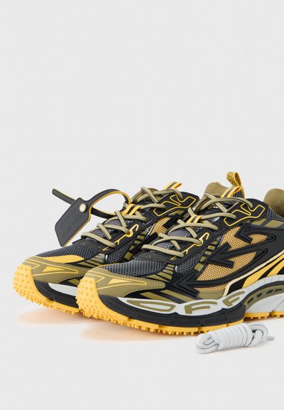 Αθλητικά παπούτσια σε μαύρο και κίτρινο χρώμα με υλικά από δίχτυ και καουτσούκ, με ανάγλυφη σόλα, αντίθετα σχέδια και γκρι κορδόνι.