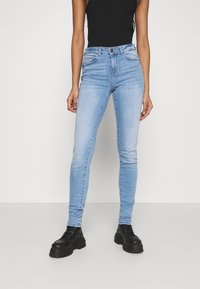 Ljust blå skinny jeans i denim, med hög midja, standard femficksdesign och subtil blekning. Matcher med svarta platåstövlar.