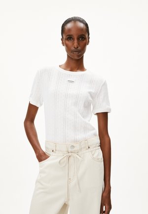 White short-sleeve T-shirt with textured vertical stripes and a round neckline. Paired with loose beige pants featuring a drawstring waist.