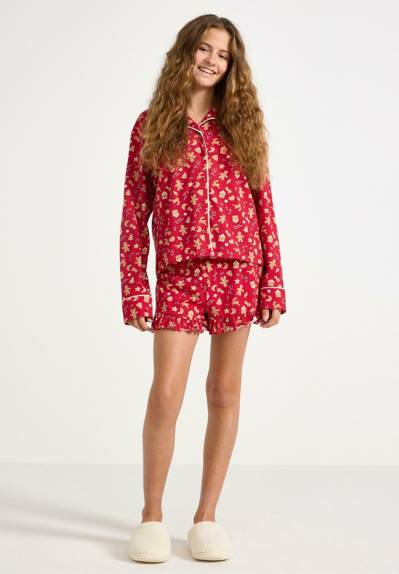 Rode pyjama set met bloemenpatroon, longsleeve shirt met kraag en afgewerkte randen, en gerimpelde shorts. Zachte textuur.