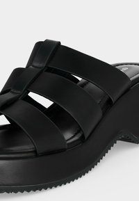 Μαύρο πλατφόρμα σανδάλι με τρεις φαρδιές δερμάτινες λωρίδες και ραβδωτή σόλα για καλύτερη πρόσφυση.