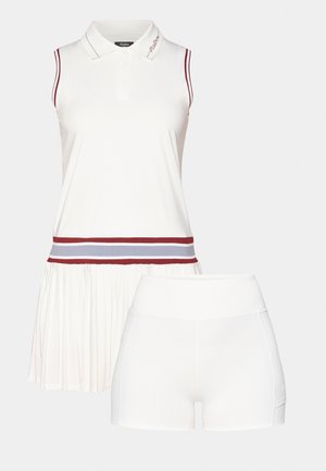 Balta bez piedurknēm polo kleita ar plisētu svārku un sarkanu un pelēku joslu jostas vietā, kopā ar baltām augstām šortiem.