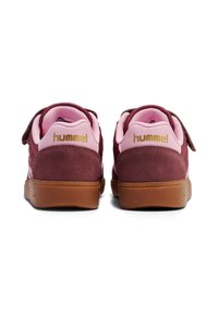 Bordeauxrote und pinke Sneaker mit einem Obermaterial aus Wildleder und Mesh. Verfügt über einen Klettverschluss und eine Laufsohle aus Kautschuk in Kaugummifarben. „Hummel“-Logo in Gold auf der Ferse.