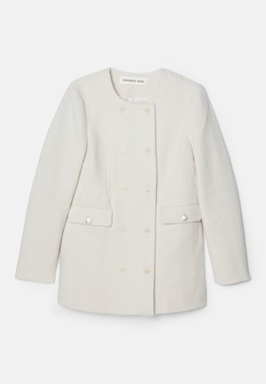 Manteau blanc à double boutonnage en tissu texturé, col rond et deux poches avant, avec des accents de boutons décoratifs.