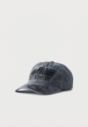 Temno siva baseball kapa z vezenim črnim napisom »Couture« in dekorativnim vzorcem spredaj in na robu vizirja, na enemostavnem svetlem ozadju.