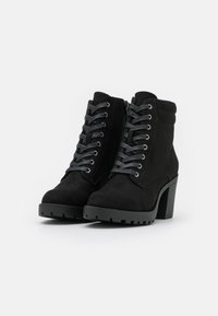 Stivali alla caviglia in suede nero con tacco spesso, caratterizzati da un design con lacci, occhielli in argento e una zip laterale. Suola testurizzata e resistente.