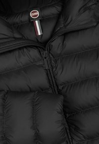 Črna puffer jakna s quiltnim dizajnom. Ima zapiranje na zadrgo, oznako logotipa in horizontalne šive. Gladka tekstura, lahkoten material.