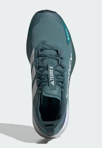 Scarpa sportiva verde con una tomaia in rete, accenti bianchi, finitura testurizzata e suola flessibile. Caratterizzata da un logo prominente e lacci resistenti.