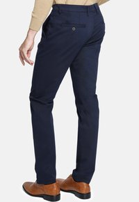 Pantalones navy con un ajuste entallado, fabricados en un tejido suave. Presenta bolsillos traseros con detalles de botón y una cinturilla bien terminada.