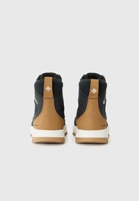 Bottes de randonnée imperméables noires et beiges avec un col rembourré, vues de l'arrière, mettant en valeur la marque et les matériaux texturés.