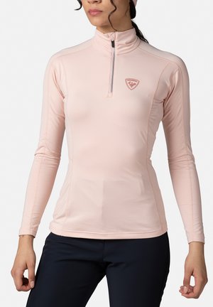 Lichtroze lange mouw top met een halve ritssluiting kraag; gemaakt van glad, rekbaar materiaal; beschikt over een logo op de borst en naaddetails.