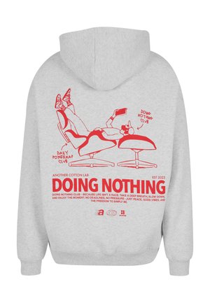 Light gray hoodie with red illustration of a person lounging on a chair, holding a phone, and the text "DOING NOTHING" with a motivational message.