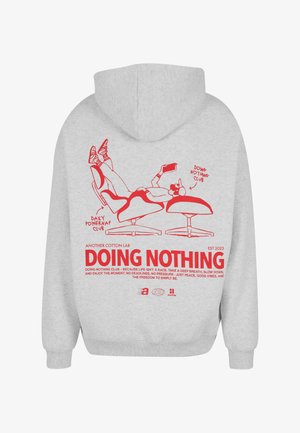 Jasnoszara bluza z kapturem z czerwoną ilustracją osoby relaksującej się na krześle, trzymającej telefon oraz tekstem "NIC NIE ROBIĘ" z motywującym przesłaniem.