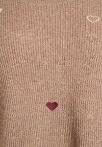Maglione a coste marrone con un piccolo cuore bordeaux e un ricamo di un cuore bianco. Tessuto morbido con scollatura rotonda.
