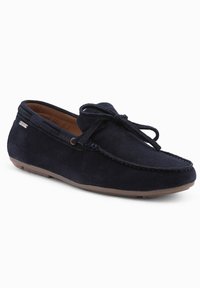 Marineblaues Wildleder-Mokassin mit gestickten Details und einer Schleifen-Schnürung, ausgestattet mit einem beige Innenfutter und einer flexiblen Gummisohle.