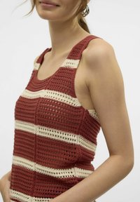 Gehaakte tanktop in roestbruin met crèmekleurige strepen, voorzien van een textuurpatroon en een mouwloos ontwerp. De stof heeft een losse breistruktuur.