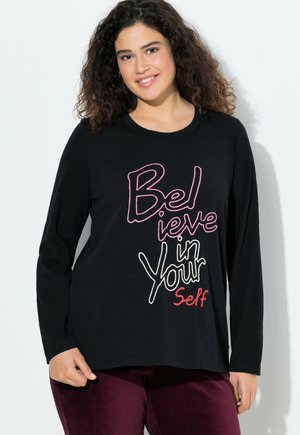 Zwarte longsleeve shirt met multikleurige tekst "Geloof in Jezelf" op de voorkant. Zachte stof met een ronde halslijn en een relaxed fit.