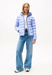Lichtpaarse pufferjack met horizontale naden, een capuchon, ritssluiting en een zwarte binnenvoering, gecombineerd met wijde blauwe jeans.