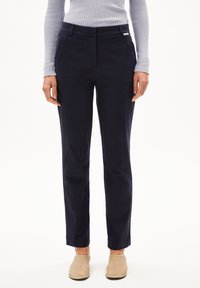 Marineblauwe broek met een rechte snit, voorzien van een platte voorkant, ceintuurlussen en een klein label op de tailleband. Gemaakt van een lichtgewicht stof.