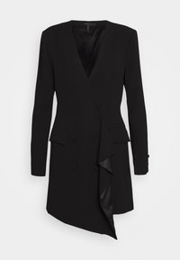Robe blazer noire croisée à manches longues, col en V profond, poches à rabat, et un ourlet asymétrique avec un volant en cascade.