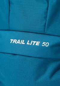 Mėlynas žygio kuprinės modelis pagamintas iš tvirto audinio, turi tinklo tekstūrą ir baltą tekstą "TRAIL LITE 50". Lygus, struktūrizuotas dizainas puikiai tinka lauko naudojimui.