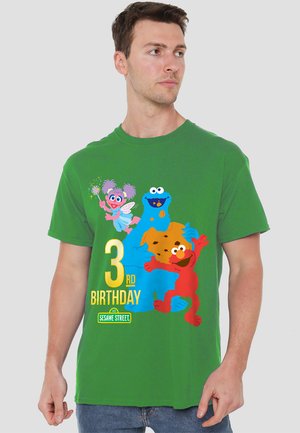 Green cotton t-shirt featuring colorful Sesame Street characters: Cookie Monster, Elmo, and Abby Cadabby, with "3rd Birthday" printed in yellow.