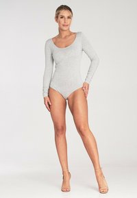 Jasnoszary, długi rękaw bodysuit z elastycznego materiału, z okrągłym dekoltem i dopasowanym krojem, zestawiony z cielistymi sandałami na wysokim obcasie.