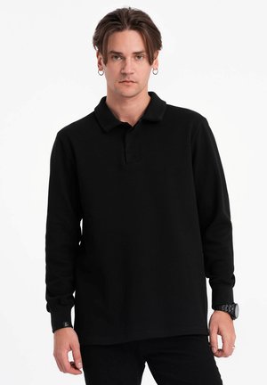Camisa polo negra de manga larga con cuello estándar, hecha de tela suave, que presenta una tapeta delantera y puños acanalados.