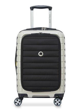Valigia di dimensioni cabine con guscio rigido, dotata di un pannello frontale in tessuto nero, dettagli laterali color crema e quattro ruote. Manico estraibile incluso.
