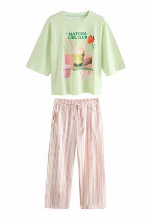 Világoszöld, túlméretezett póló „Matcha Girl Club” felirattal, rózsaszín makaronokkal és csíkos, rózsaszín, zsinóros nadrág szettel.