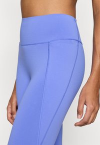 Κολάν ψηλόμεσο, εφαρμοστό σε ανοιχτό μπλε, με ραφές flatlock και λείο, ελαστικό ύφασμα για άνεση και ευελιξία.