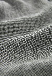 Textil med ett svartvitt rutmönster, slät textur och lätt utseende, som visar fina nätliknande vävdetaljer.