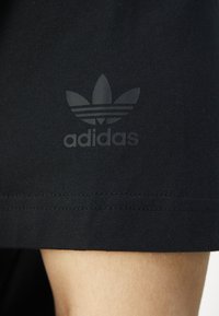 Black cotton shorts featuring a stamped Adidas logo with three stripes, located near the hem, and smooth texture with neat stitching.