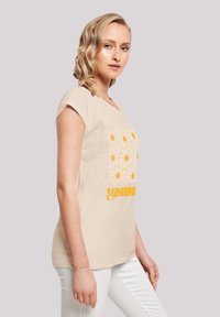 Beige t-shirt featuring a floral design with yellow daisies and the word "summer" in bold font. Short sleeves and a relaxed fit.