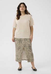 Beżowy sweter z krótkim rękawem w połączeniu z midi spódnicą w leopardzi wzór z rozcięciem z przodu. Czarne baleriny dopełniają cały strój.