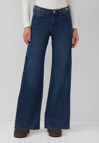 Wijde spijkerbroek in donkerblauw denim, met een hoge taille, knoopsluiting en accenten van goudkleurig metaal aan de tailleband.