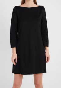 Robe noire avec décolleté carré, manches trois-quarts et coupe décontractée. Fabriquée en tissu doux et lisse avec un minimum de détails.