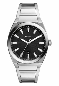 Montre en acier inoxydable argenté avec un cadran noir texturé, des index horaires blancs et un affichage de la date. Elle possède une lunette polie et un bracelet à maillons.