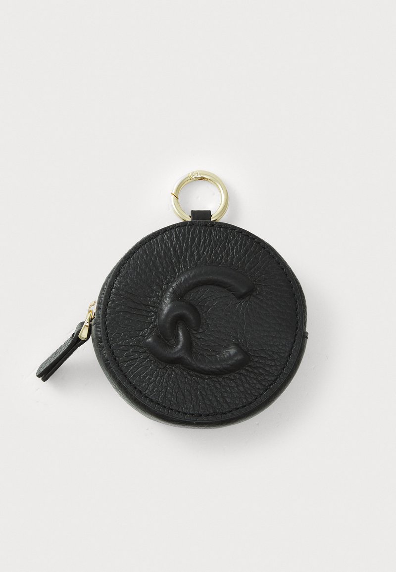 Black leather round coin purse with embossed logo design, featuring a gold-tone ring and zipper closure, textured surface, and a small leather tab.