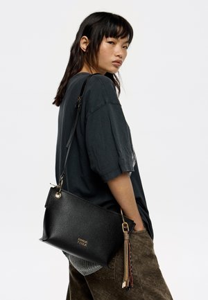 Bolso de mano de cuero negro con un acabado texturizado, cierre de cremallera y un borlas decorativa. Correa ajustable para mayor versatilidad.