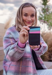 Black leather cardholder with three colored panels: blue, pink, and gray. Smooth texture with a logo embossed on the bottom right.