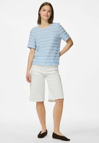 Gaiši zils, teksturēts T-krekls ar horizontālām svītrām; apvienots ar baltām ceļgalu garuma šortiem un brūnām plakano apavu sandālēm.