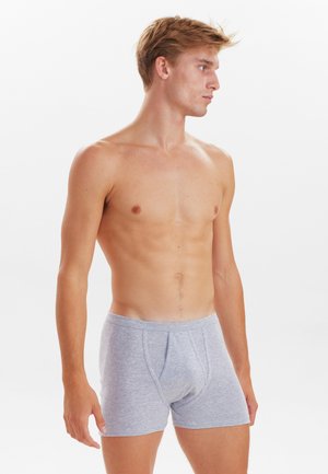 Grå bomulds-boxershorts med en blød tekstur, med en frontåbning og en elastisk talje, båret af en model med en slank kropsbygning.