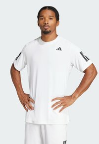 Biała koszulka sportowa z czarnym logo Adidasa i paskami na rękawach. Krótkie rękawy, okrągły dekolt, lekki materiał i luźny krój.